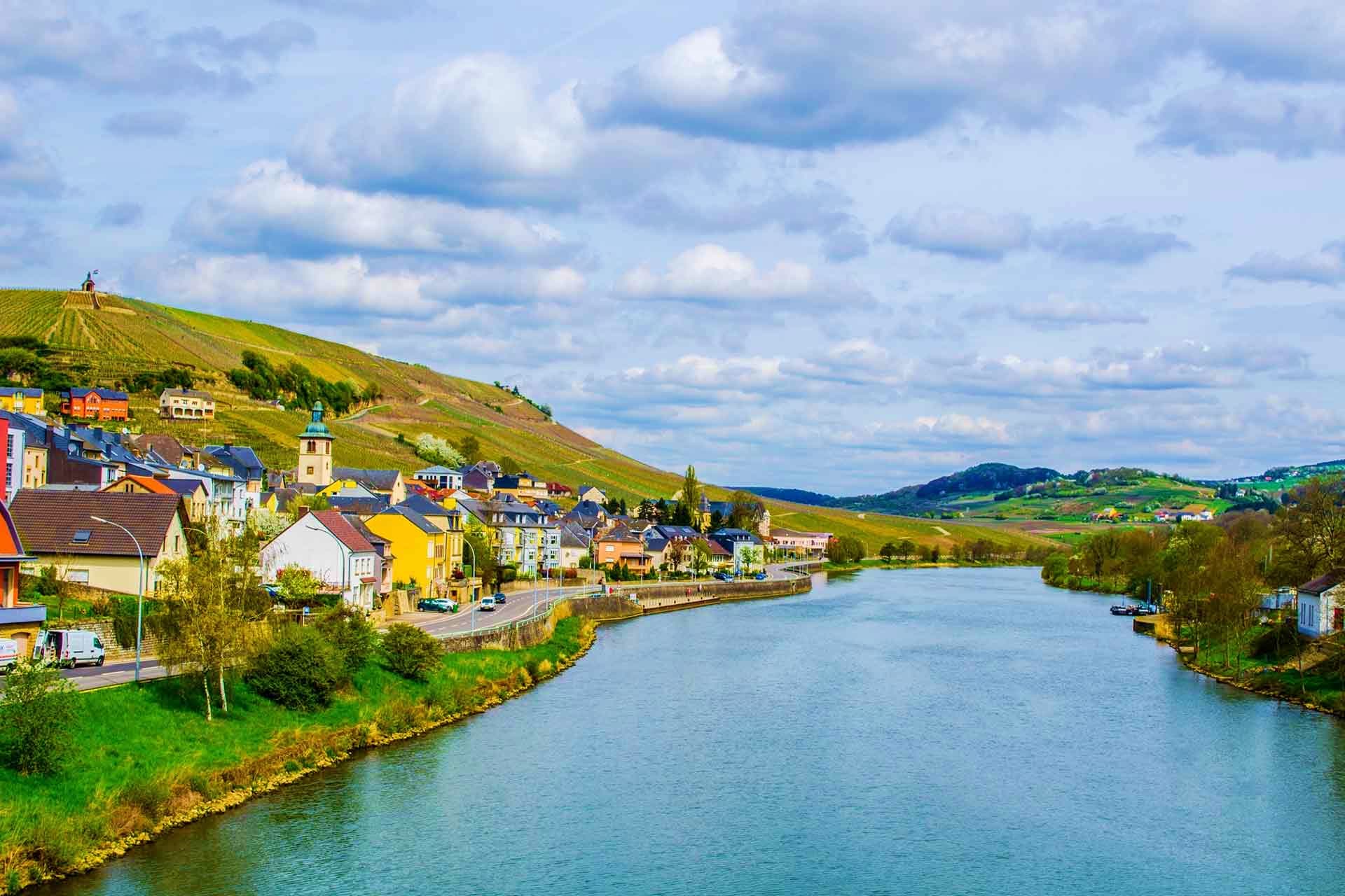 Schengen Visa Colorful riverside village in Moselle Valley Germany with vineyards on hillside and blue river, representing European travel
